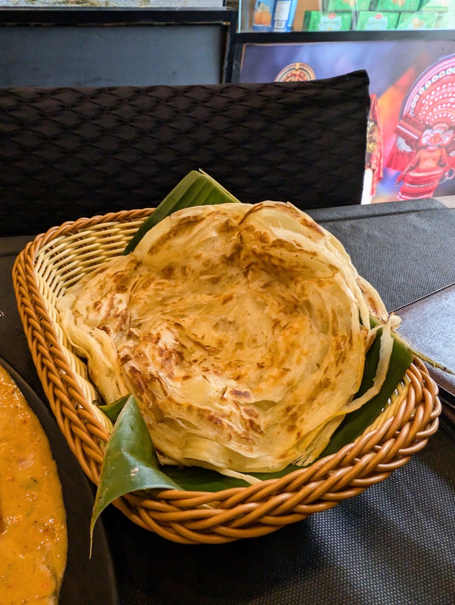 Parotta del Kerala, pane sfogliato dorato servito nel cestino su foglia di banano